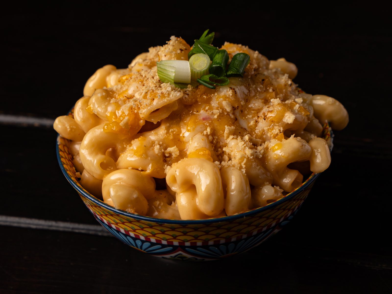 Bowl of smoked mac and cheese topped with green onion and breadcrumbs