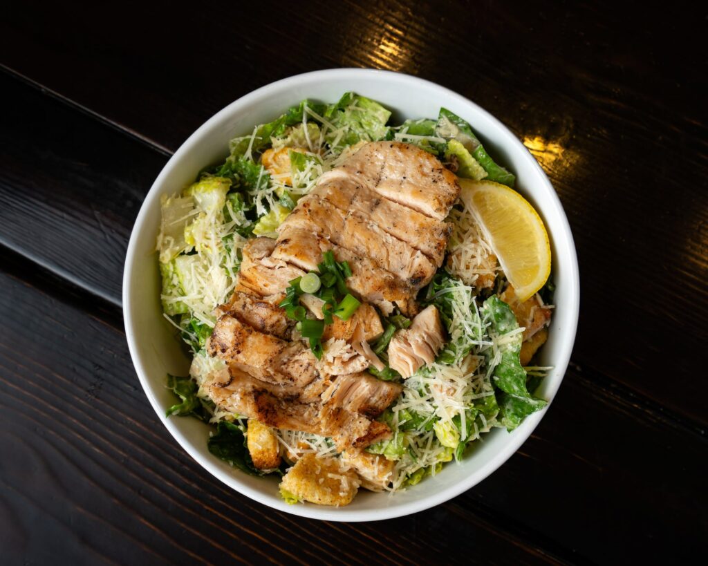 Caesar salad topped with grilled salmon and parmesan