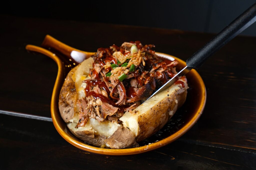 Pulled pork on a loaded baked potato with BBQ sauce and crispy onions