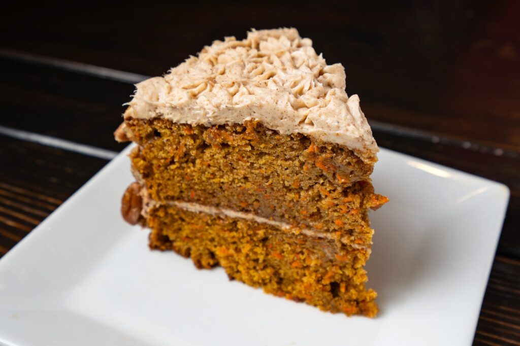 Slice of carrot cake with cream cheese frosting and pecans