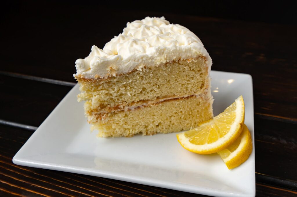 Slice of lemon layer cake with lemon wedges