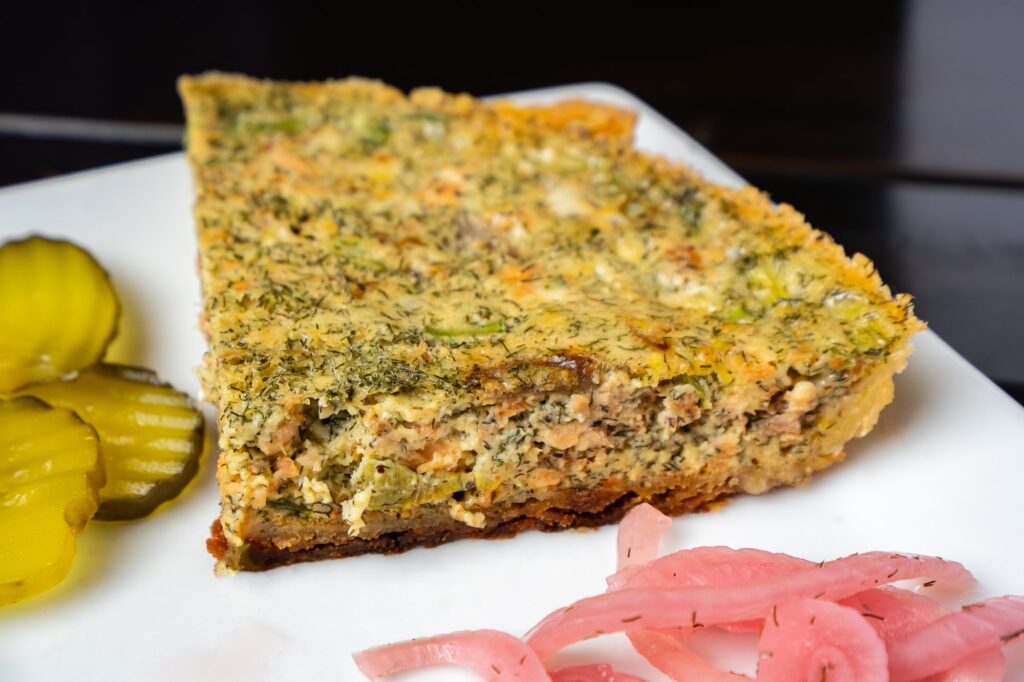 Slice of quiche with pickles and pickled onion