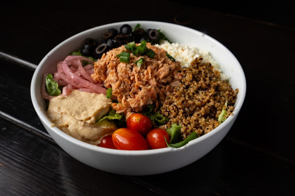 Smoked salmon grain bowl with hummus, feta, cherry tomatoes and olives