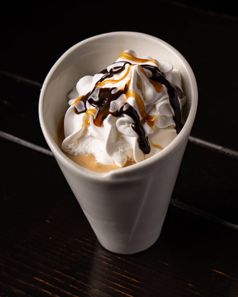 Sundae topped with whipped cream, caramel and chocolate drizzle