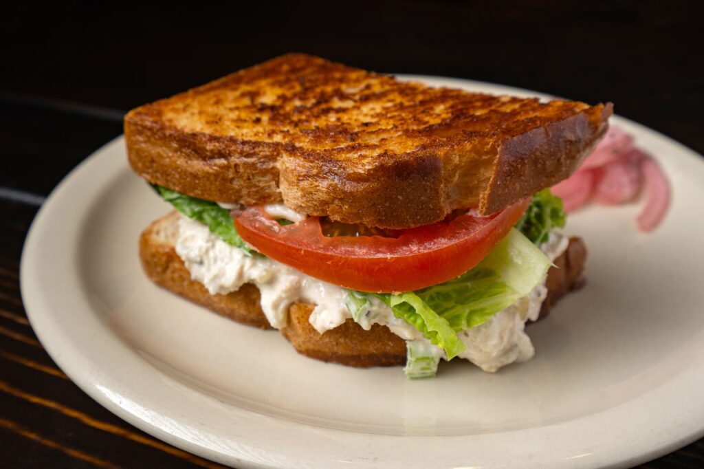 Tuna salad sandwich on toasted bread with lettuce and tomato